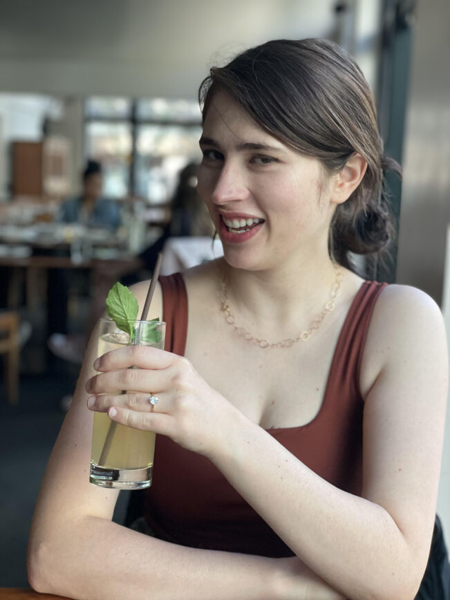 Caeli holding a drink and showing off her ring